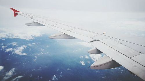 Cropped image of airplane wing flying in sky