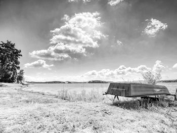 Old fishing boat upside down under tree at smooth water of lipno lake. calm windles. black and white