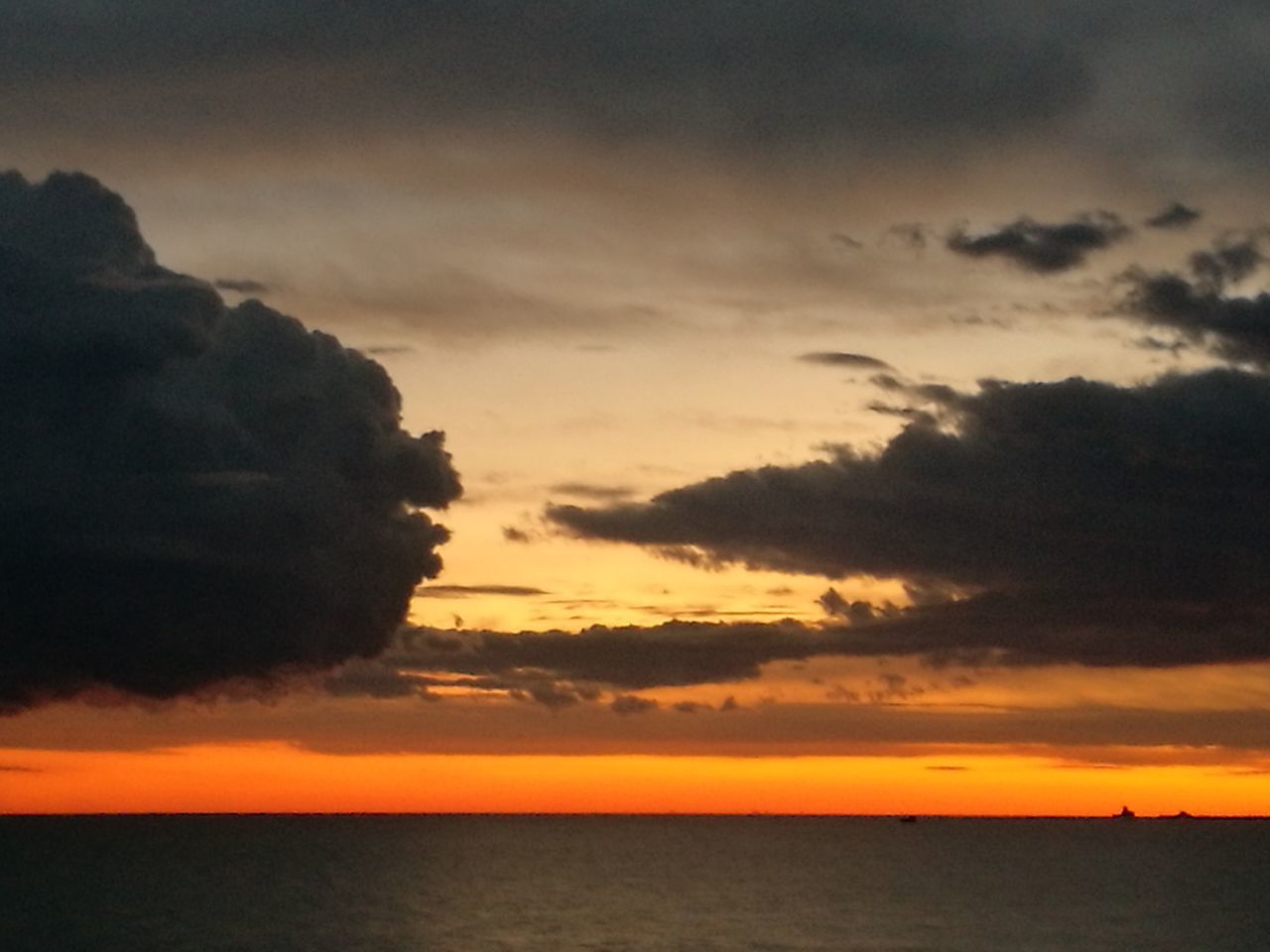 VIEW OF CALM SEA AGAINST DRAMATIC SKY