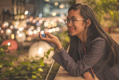 Optical illusion of smiling teenage girl touching defocused light at balcony