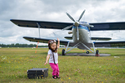 Girl on airplane at airport runway against sky