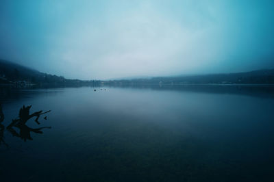 Scenic view of lake against foggy sky