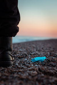 Surface level of pebble beach against sky during sunset