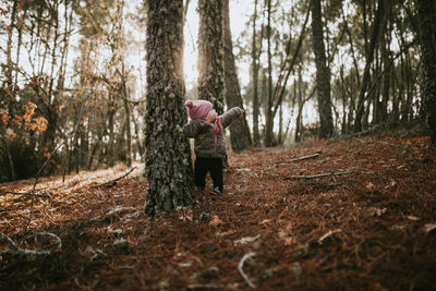 Woman standing by tree trunks in forest