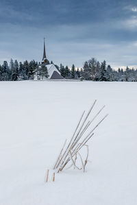 Traditional windmill on snow field against sky