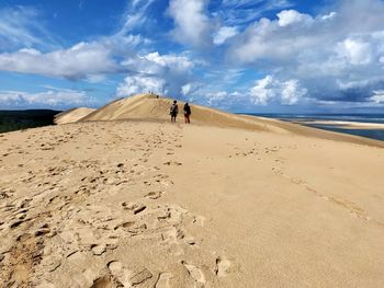 Scenic view of a people walking on dune of pilât on france against sky 