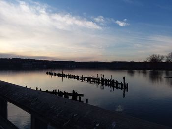 Group of people on pier at lake against sky