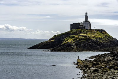 Lighthouse by sea against sky