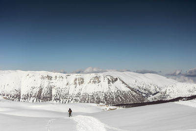 Rear view of person skiing on snowcapped mountain against sky