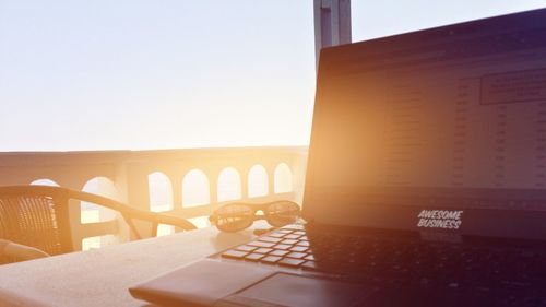 Close-up of laptop and sunglasses against clear sky