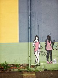 Female drawing on wall by street