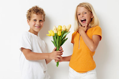 Portrait of smiling boy giving flowers to sister