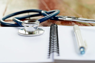 Close-up of stethoscope with spiral notebook on table