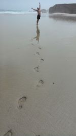 Low section of man standing on beach against sky