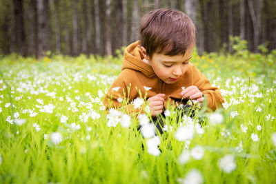 Portrait of young woman picking flowers on field