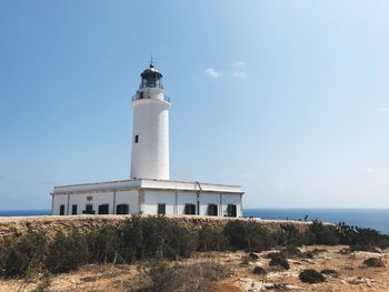 Lighthouse by building against sky