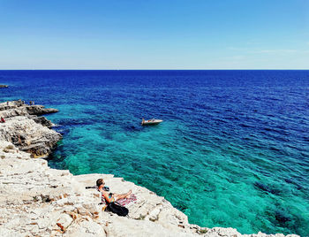 People sunbathing on rocky cliffs above sea. summer, vacation, travel, horizon.