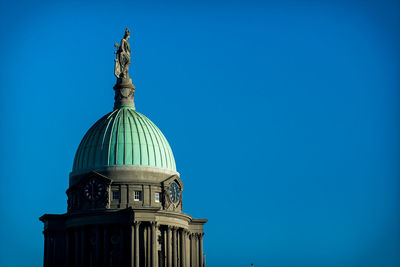 Low angle view of statue of building against blue sky