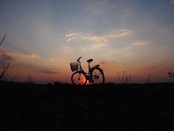 Silhouette bicycle on field against sky during sunset