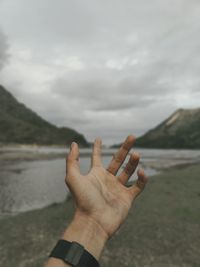 Cropped image of person hand against sky