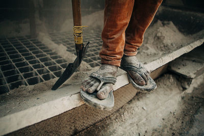 Low shot of factory worker standing with shovel