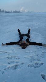 Man on snow covered shore against sky