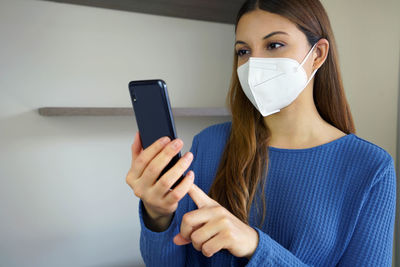 Young woman wearing mask using mobile phone