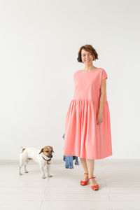 Woman with dog standing against wall