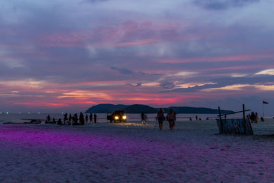 Silhouette people on beach against sky during sunset