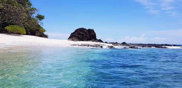 Rocks in sea against blue sky