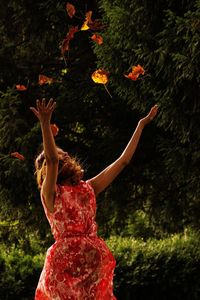 Rear view of woman standing by tree trunk