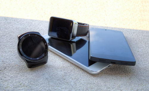 Close-up of smart phones and wristwatches