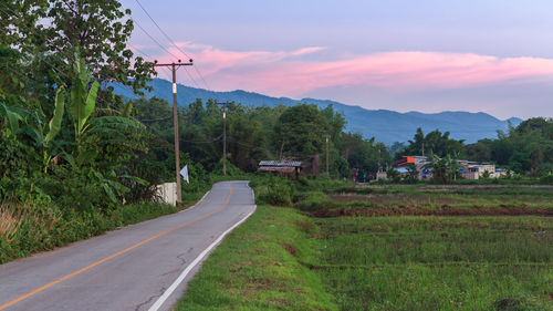 Road amidst trees and mountains against sky