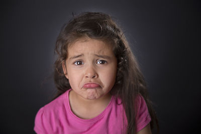 Portrait of sad girl against gray background