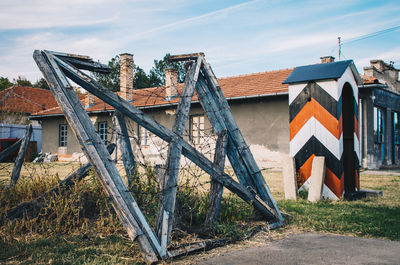 Bridge over field by buildings against sky