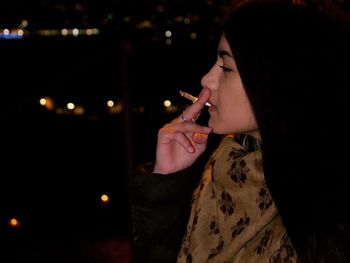 Portrait of young woman holding illuminated text at night