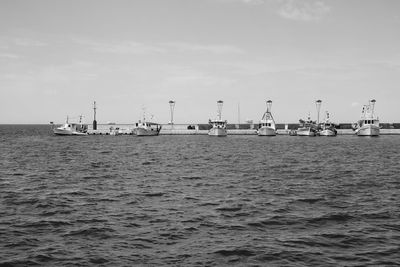 Boats moored by pier in sea against sky