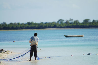 Man fishing in lake against sky