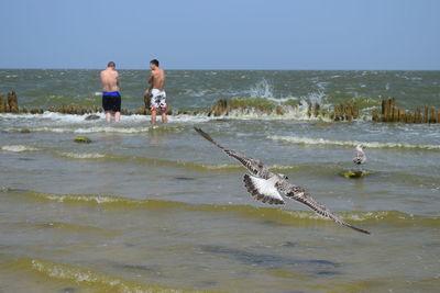 Rear view of two men standing in the ocean