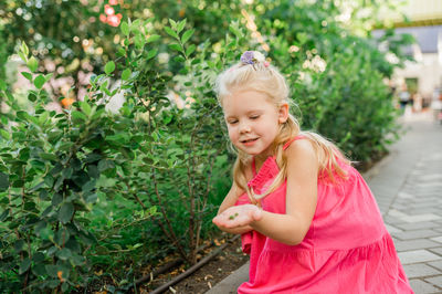 Portrait of young woman standing against plants