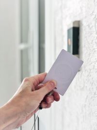 Midsection of person holding umbrella against white wall