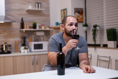 Young man sitting on table at home