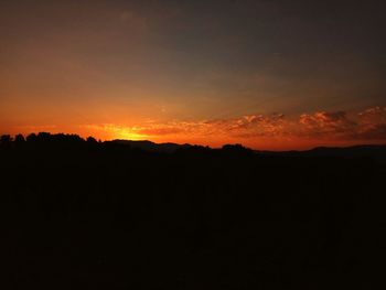 Silhouette landscape against dramatic sky during sunset