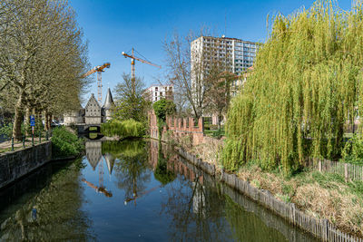 Canal amidst trees and buildings against sky