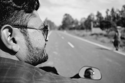Close-up portrait of man with car on road