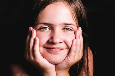 Close-up portrait of girl smiling against black background