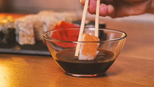 Cropped hand of woman holding drink on table