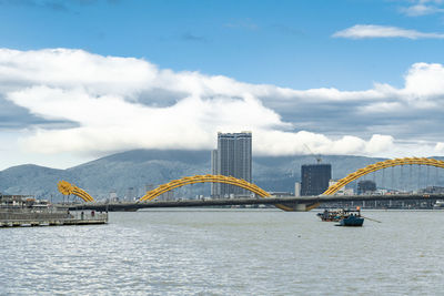 Bridge over river in city against sky