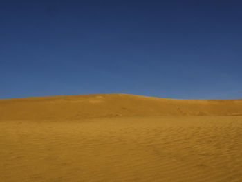 Scenic view of desert against clear blue sky