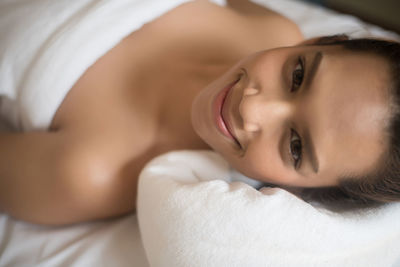 Portrait of smiling young woman lying on massage table in spa